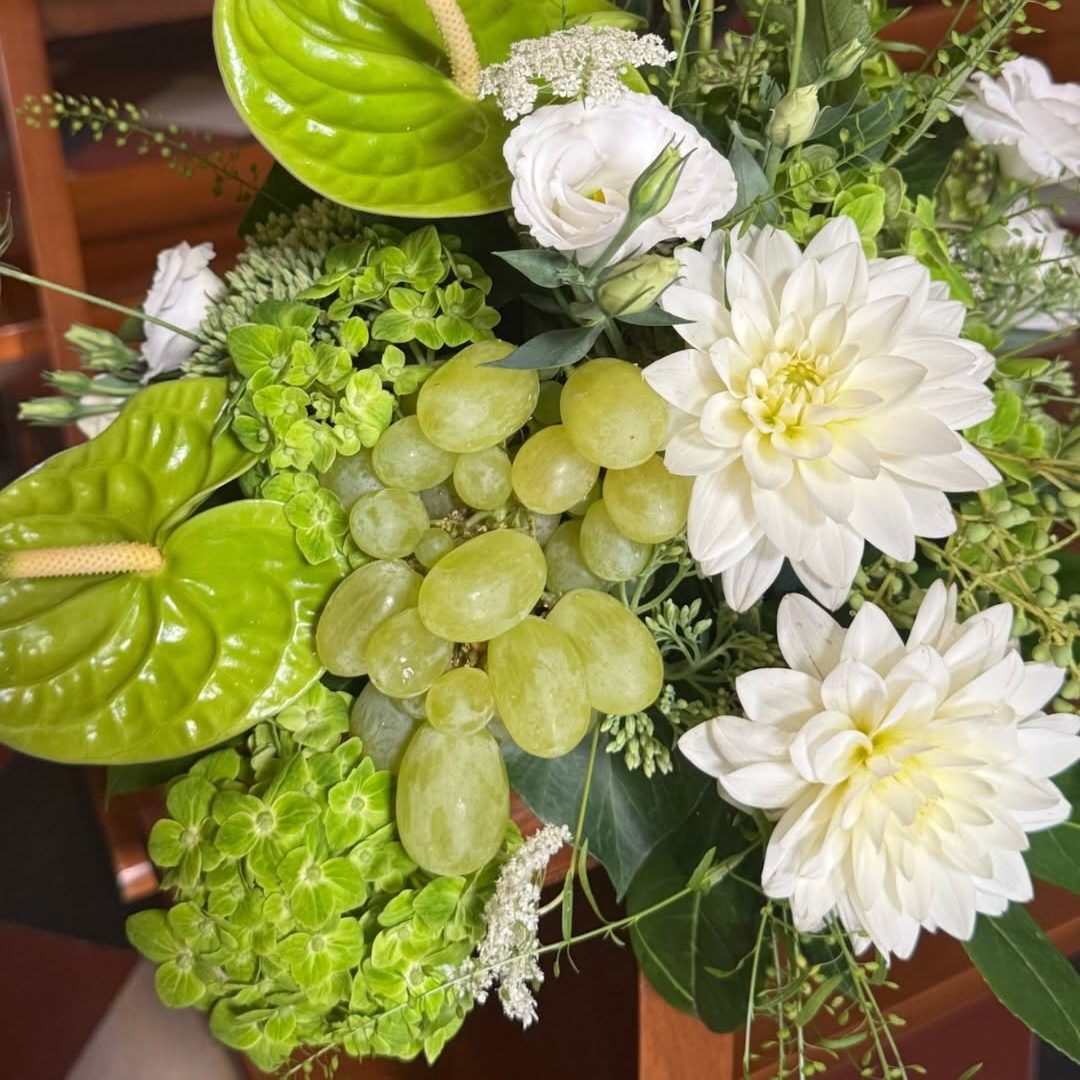 Composizione con dalie bianche, anthurium verde e grappoli d'uva