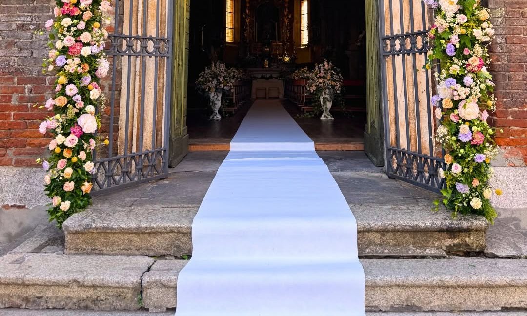 Ingresso di una chiesa decorato con colonne di fiori rosa e bianchi